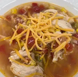Bowl of chili topped with shredded cheese, beans, and chunks of chicken