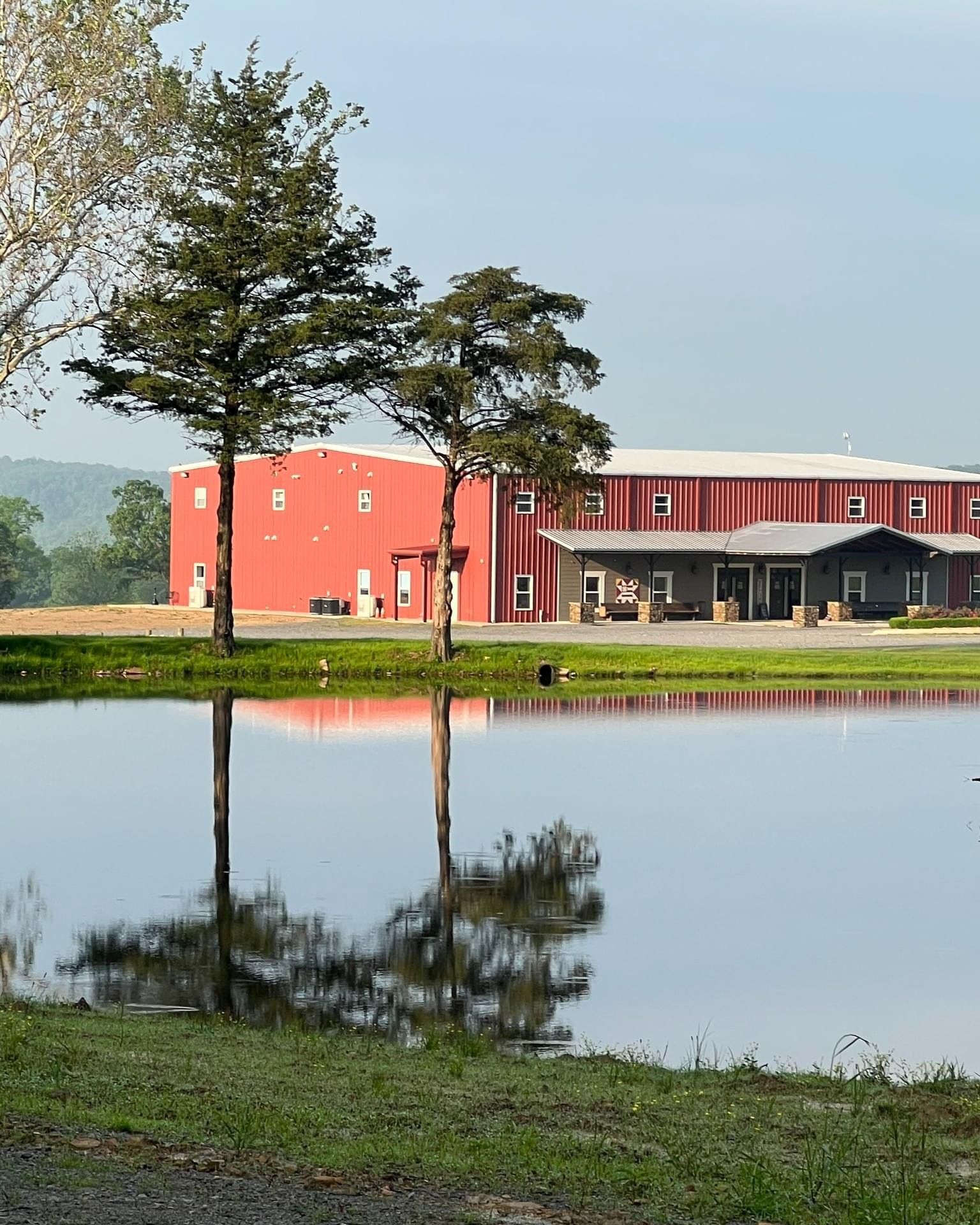 Red building by a pond, with trees and a clear reflection in the calm water.