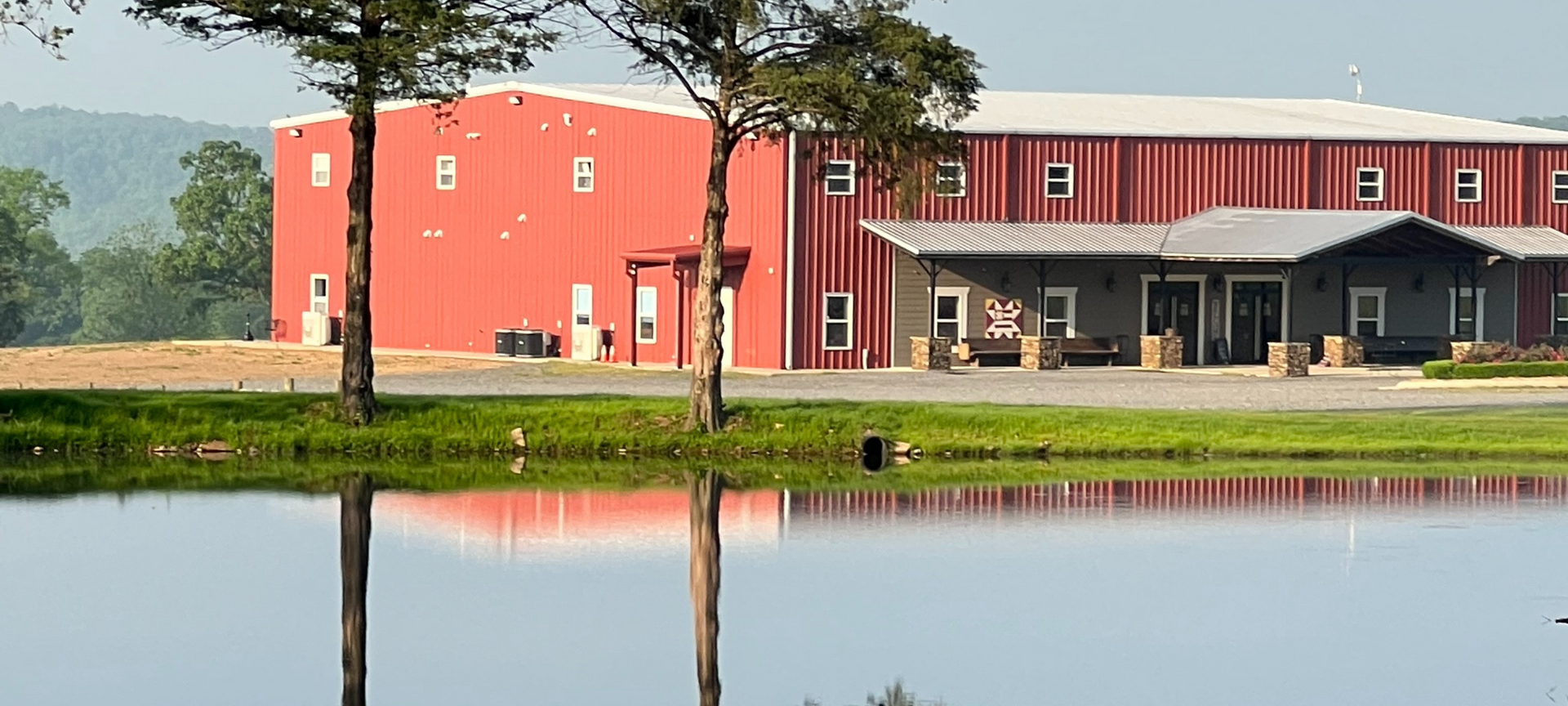 Red building by a pond, with tree reflections in calm water.