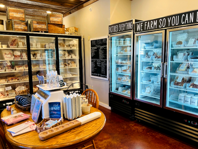 Cozy bakery café with glass display cases, pastries, and a round table stocked with drinks and snacks