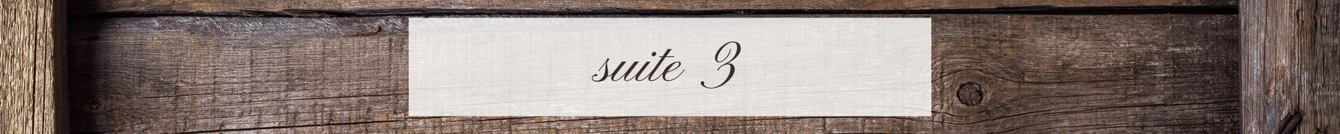 Rustic wooden sign with a small white label reading “suite 3”