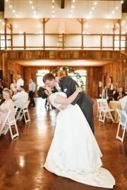 Bride and groom embracing during a wedding reception in a rustic, warmly lit hall