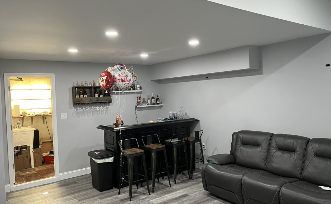 A living room with a couch , bar and stools.