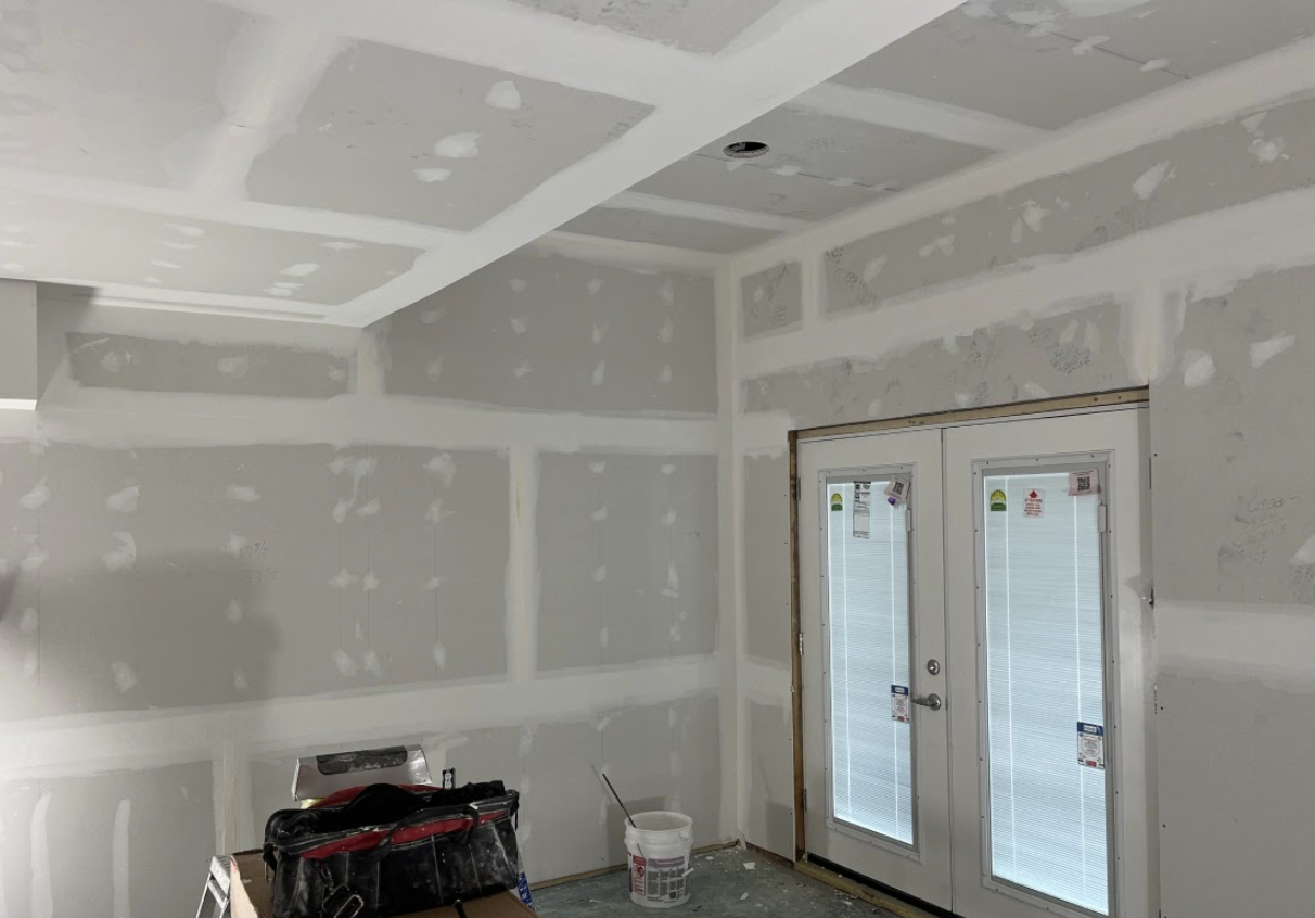 A room with a lot of drywall and a door.