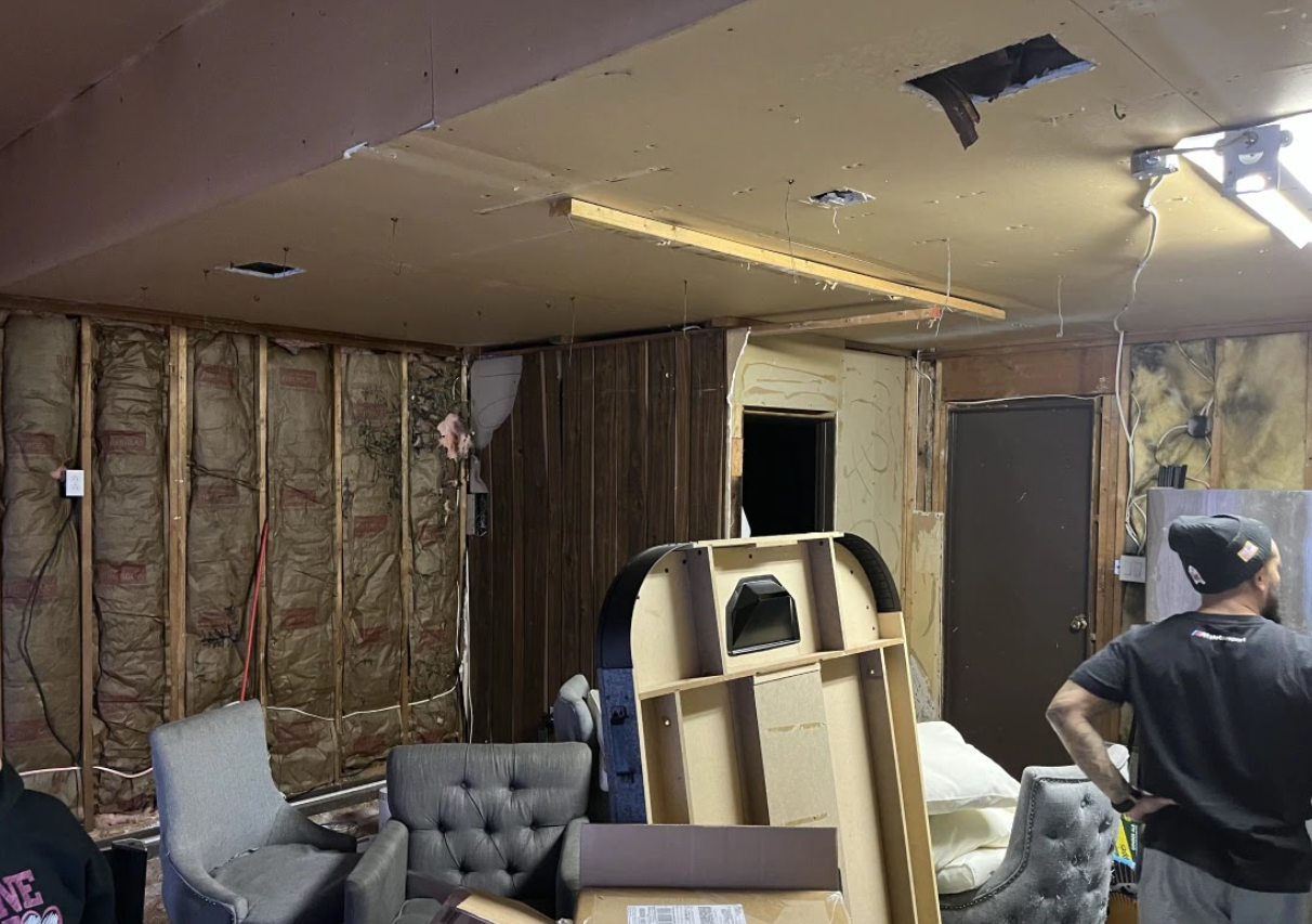 A man is standing in a room filled with furniture and boxes.