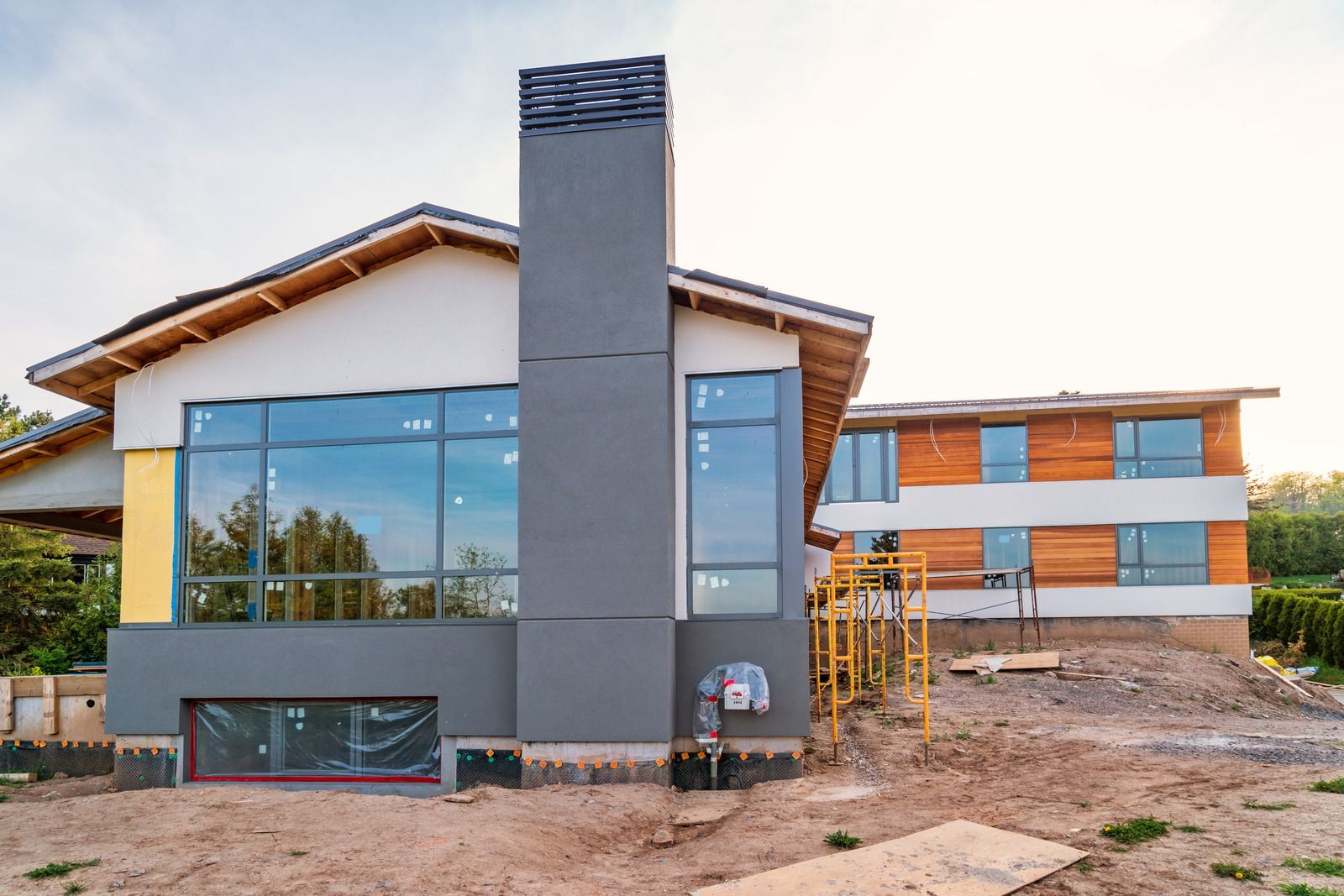 A large house is being built in the middle of a dirt field.