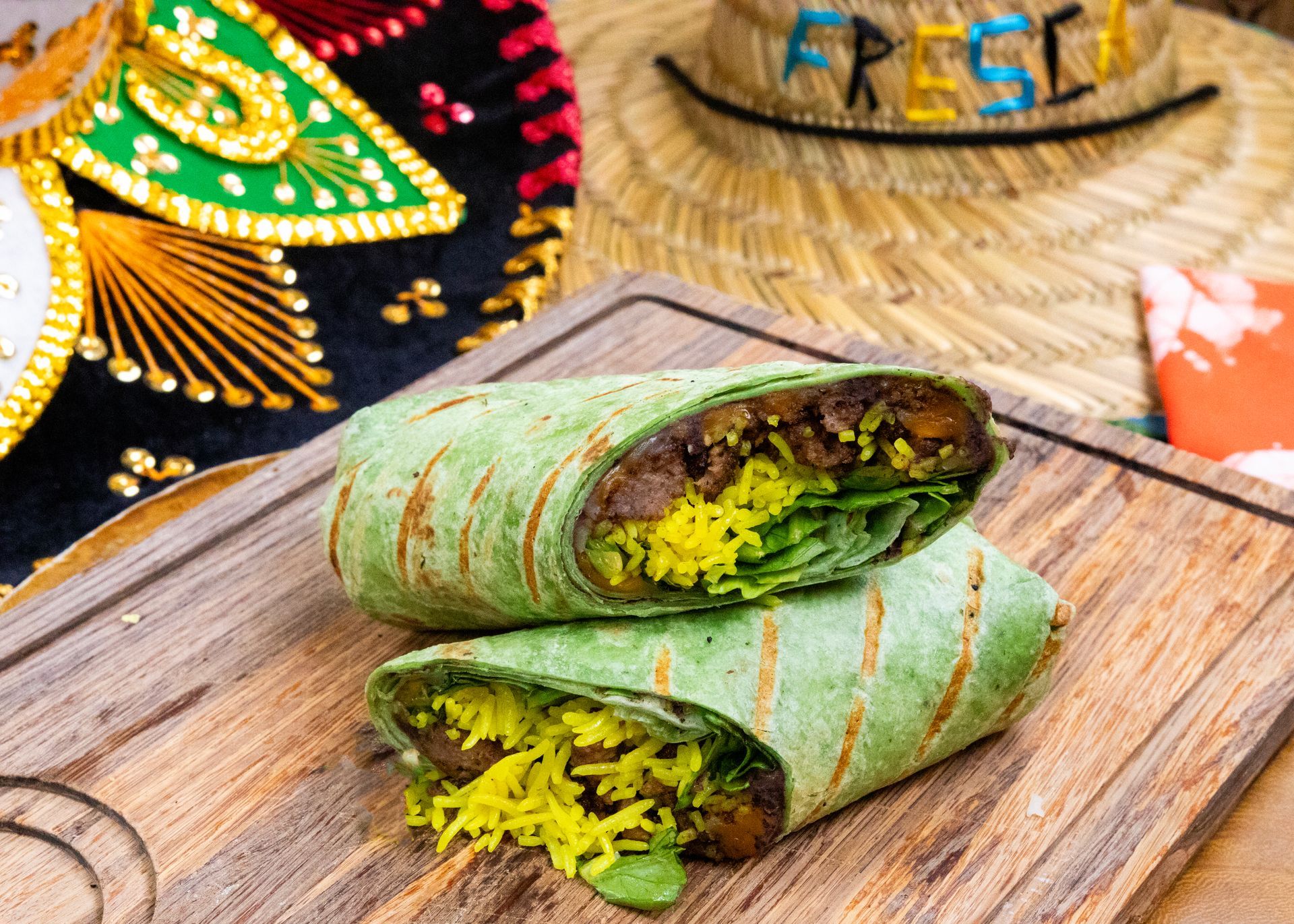 A tortilla wrap is cut in half on a wooden cutting board.