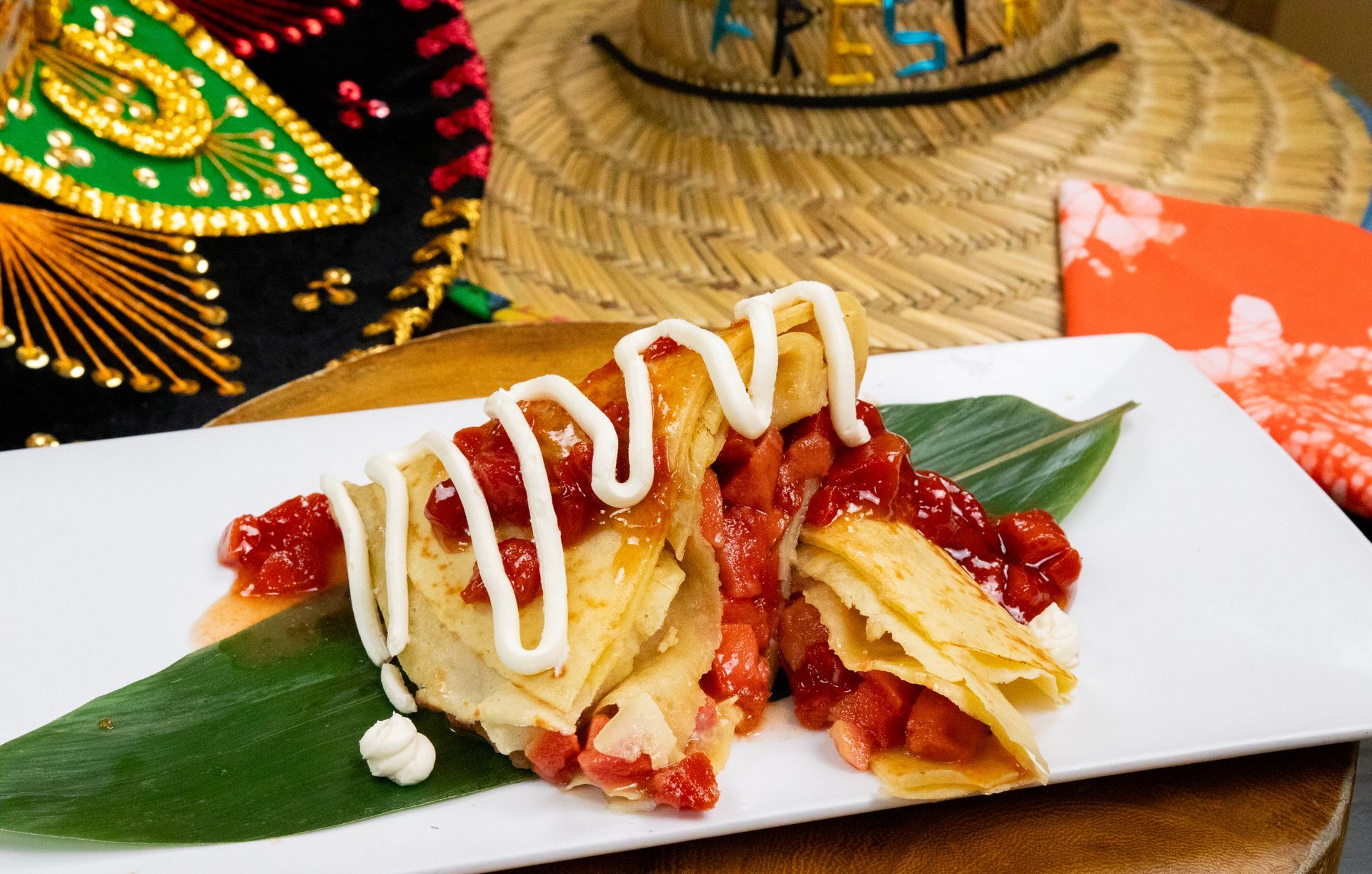 A close up of a plate of food on a table with a sombrero in the background.