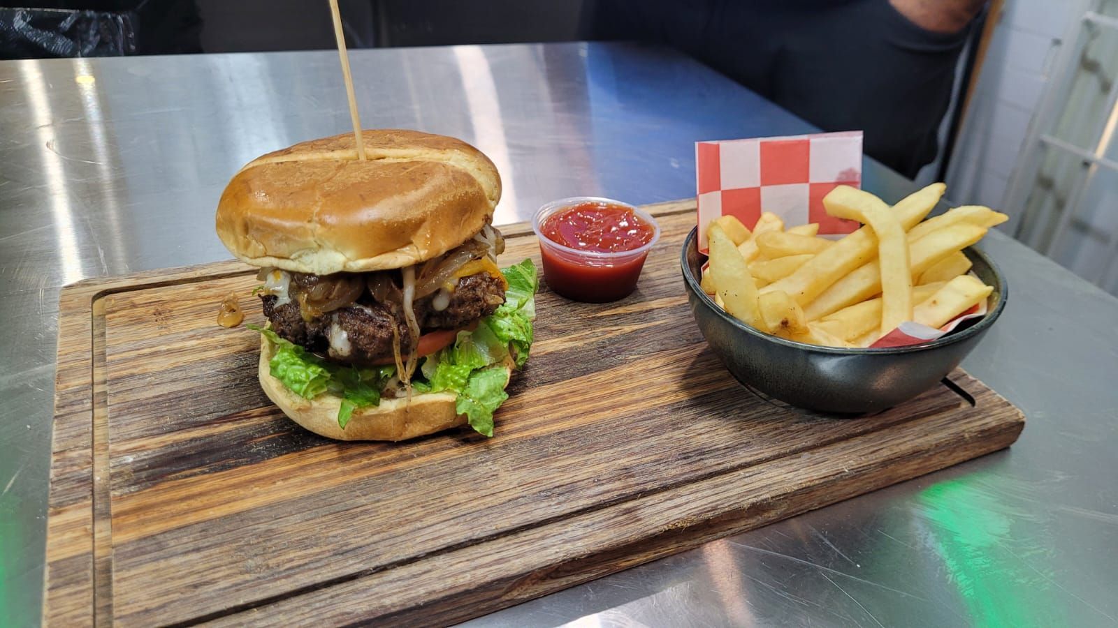 A hamburger and french fries are on a wooden cutting board.