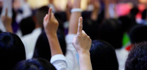 Red tractor pulling a green and yellow planter in a field on a sunny day.