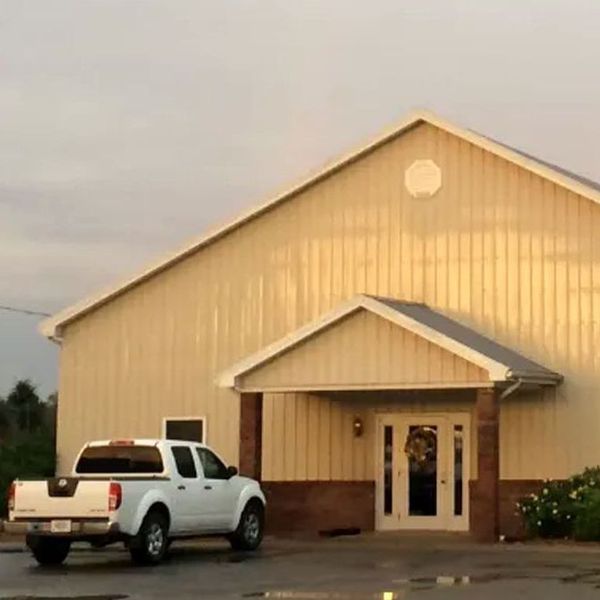 A white truck is parked in front of a large building.