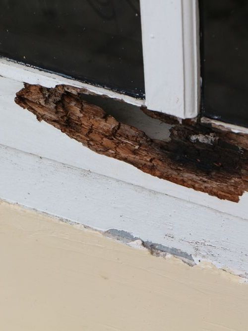 A close up of a window sill with a piece of wood sticking out of it.