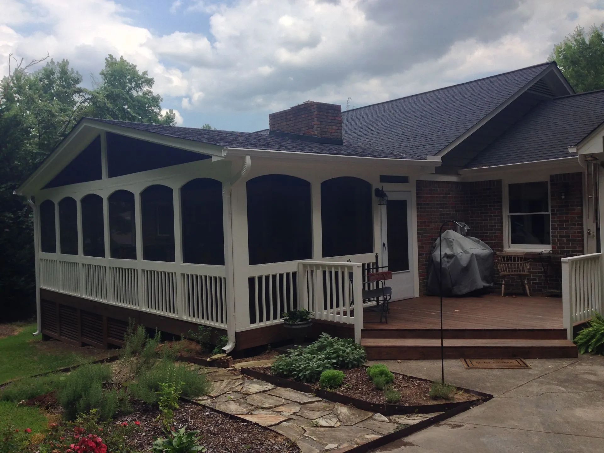 A screened in porch sits in front of a brick house