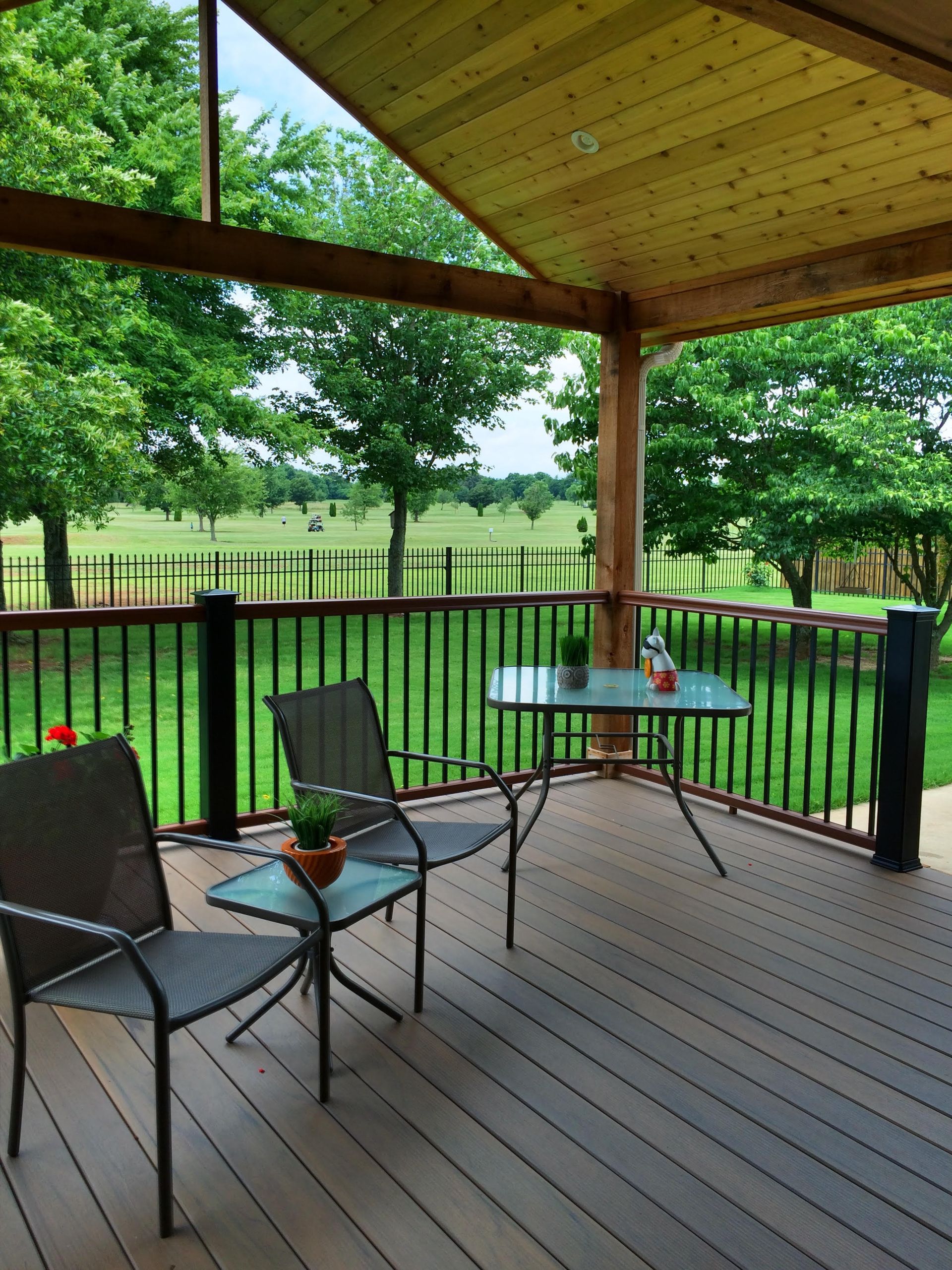 A deck with chairs and a table with a view of a field