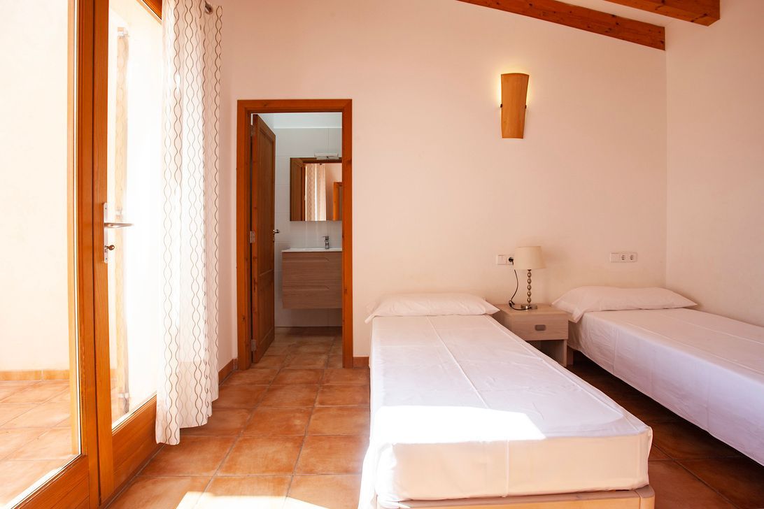 Un dormitorio con dos camas y una puerta que conduce a un baño.