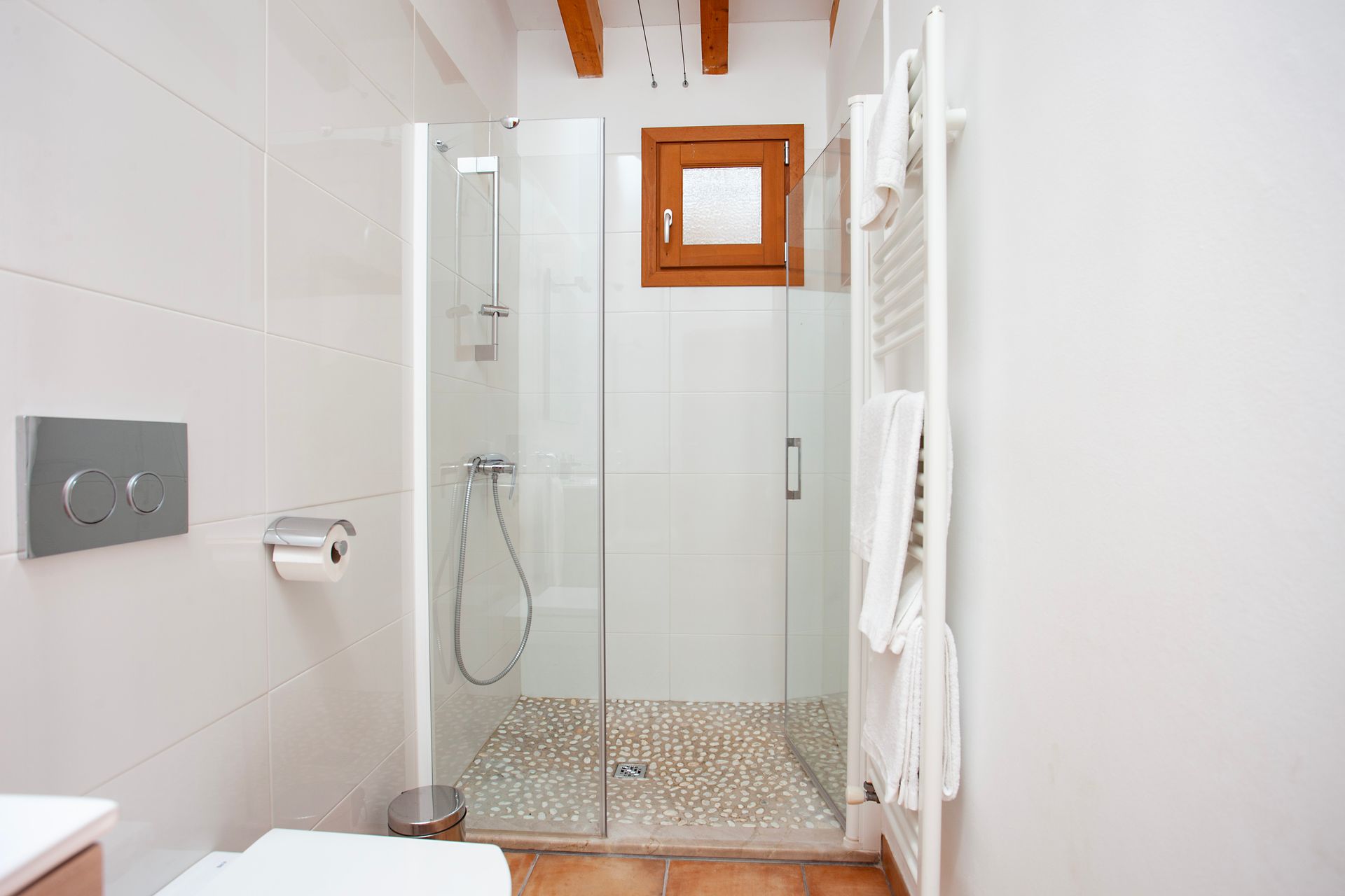 Un baño con ducha a ras de suelo y un aseo.