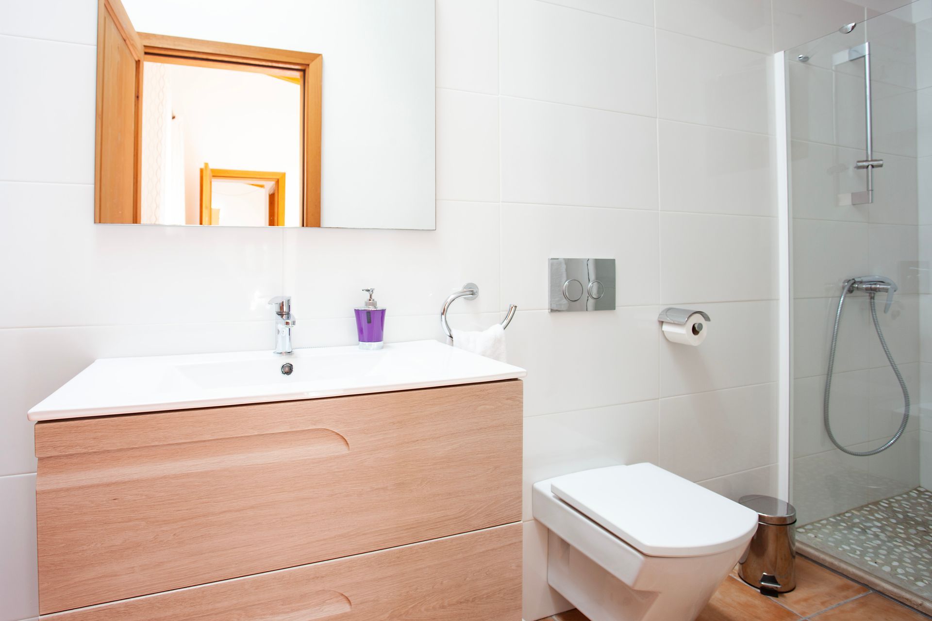 Un baño con inodoro, lavabo, espejo y ducha.