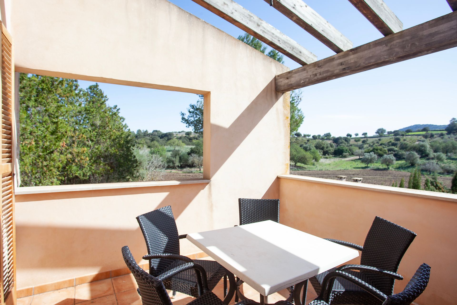 Un balcón con mesa y sillas y una gran ventana.