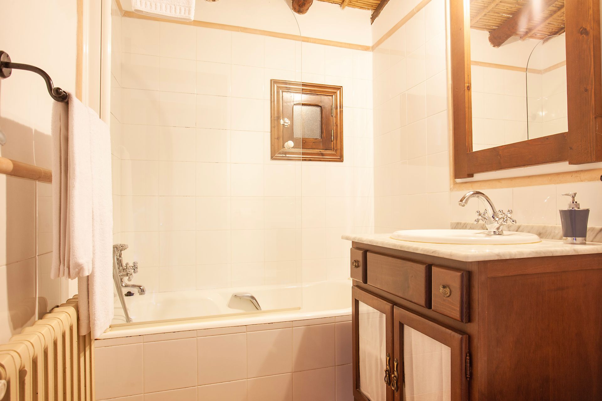 Ein Badezimmer mit Waschbecken, Badewanne, Spiegel und Heizkörper.