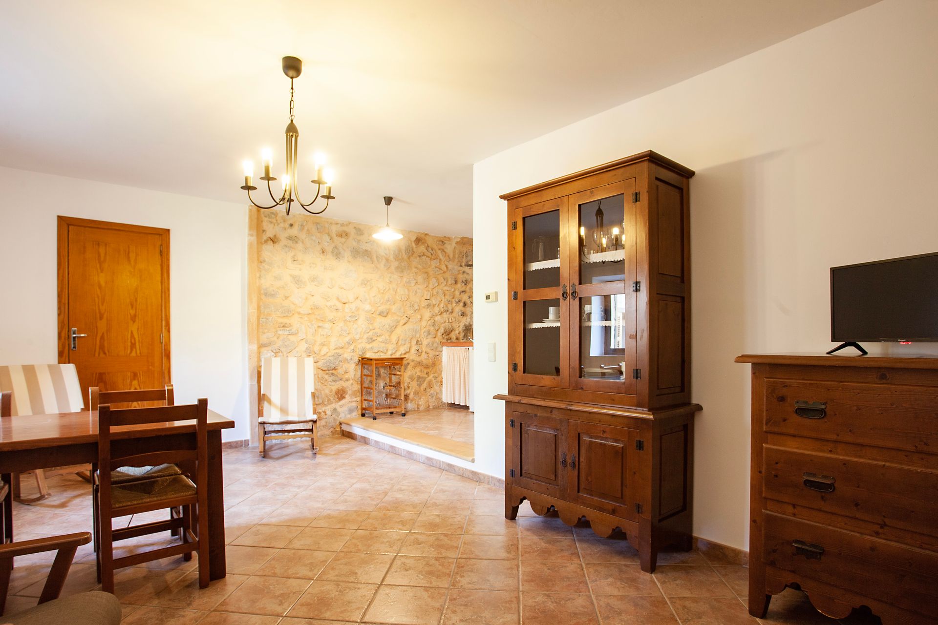 Ein Wohnzimmer mit Tisch, Stühlen, Kommode und Fernseher.