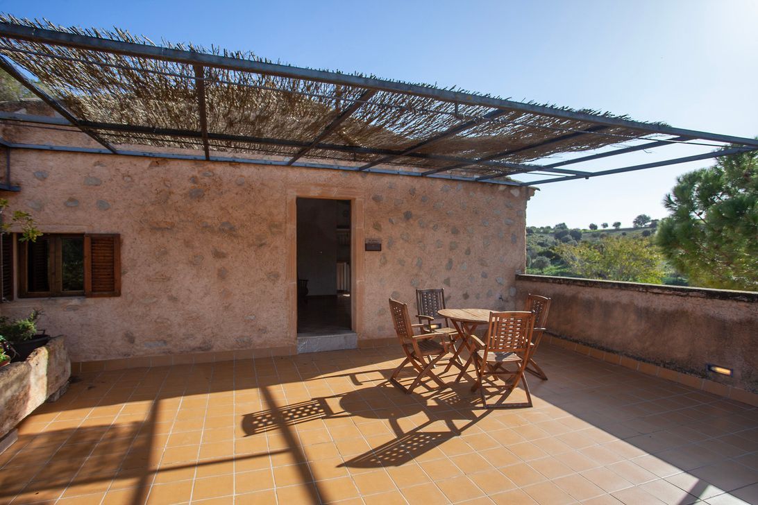 Una terraza en la azotea con una mesa y sillas bajo un dosel.