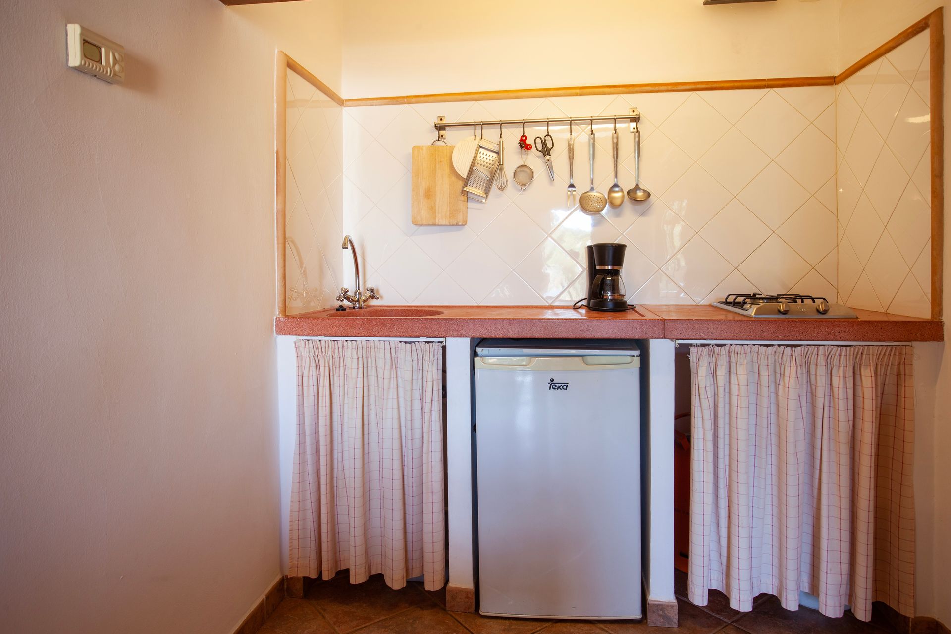 Eine kleine Küche mit Spüle, Kühlschrank und Kaffeemaschine.