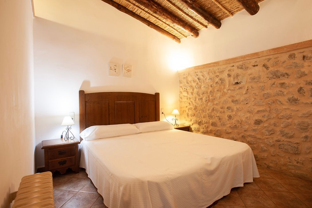 Un dormitorio con una cama grande y una pared de piedra.