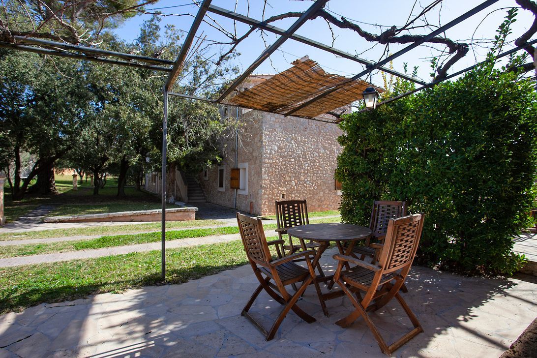 Un patio con una mesa y sillas bajo una pérgola.