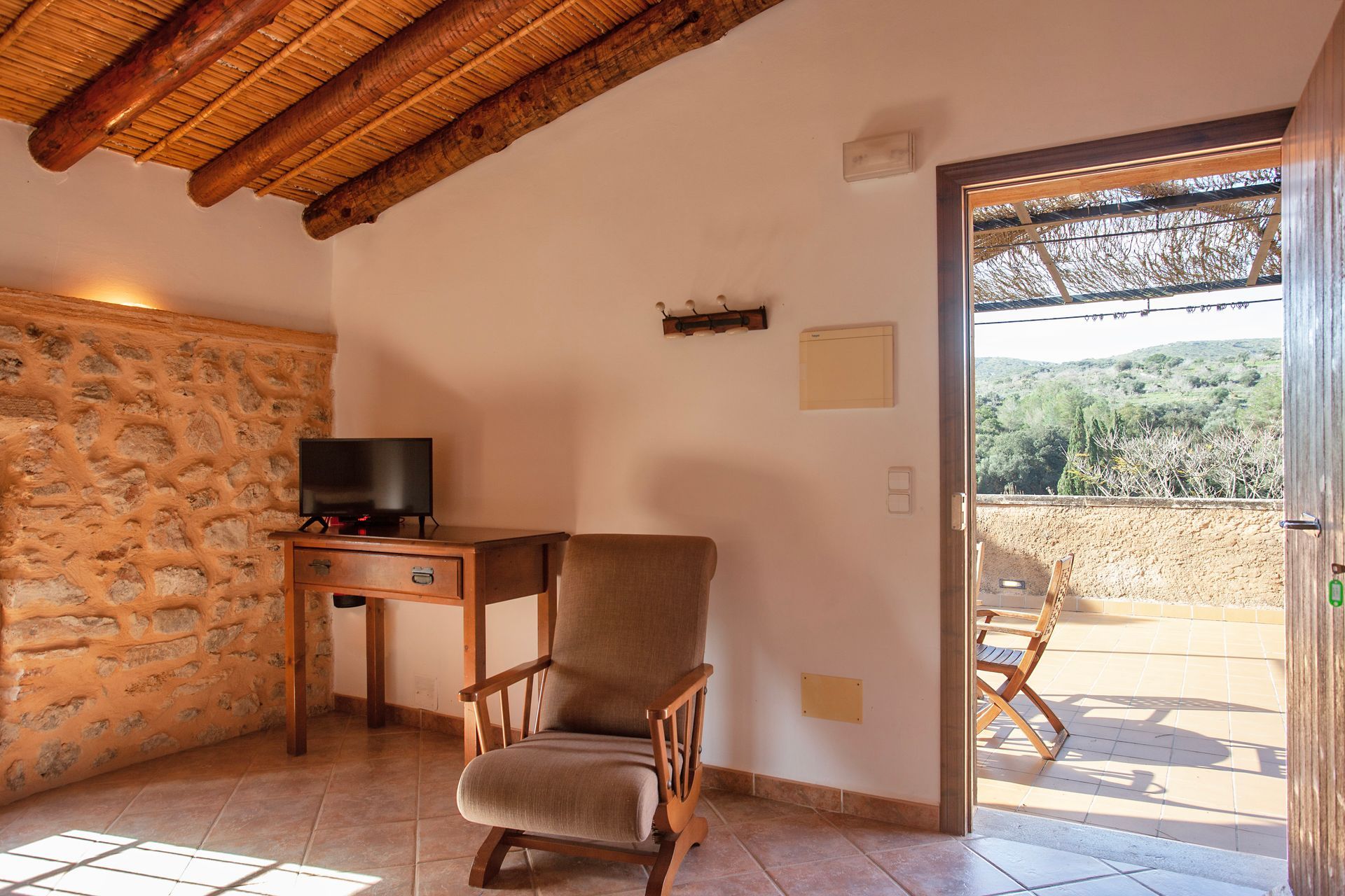 Ein Wohnzimmer mit Sessel, Schreibtisch und Fernseher.