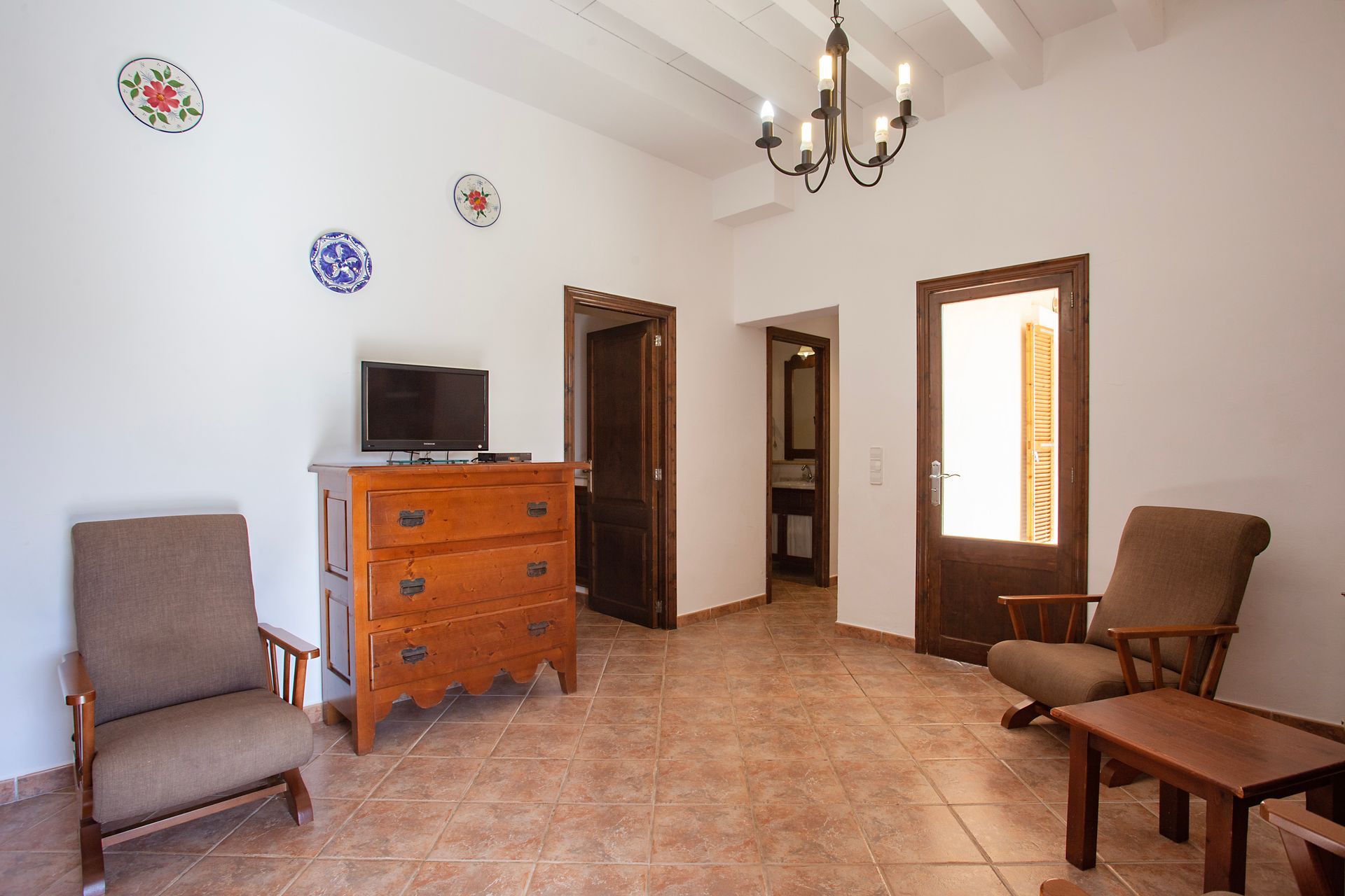 Una sala de estar con una cómoda, sillas y un televisor.