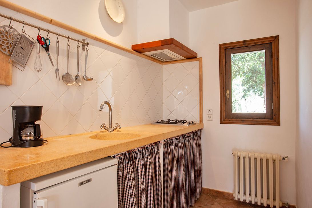 Una cocina con fregadero, estufa y ventana.