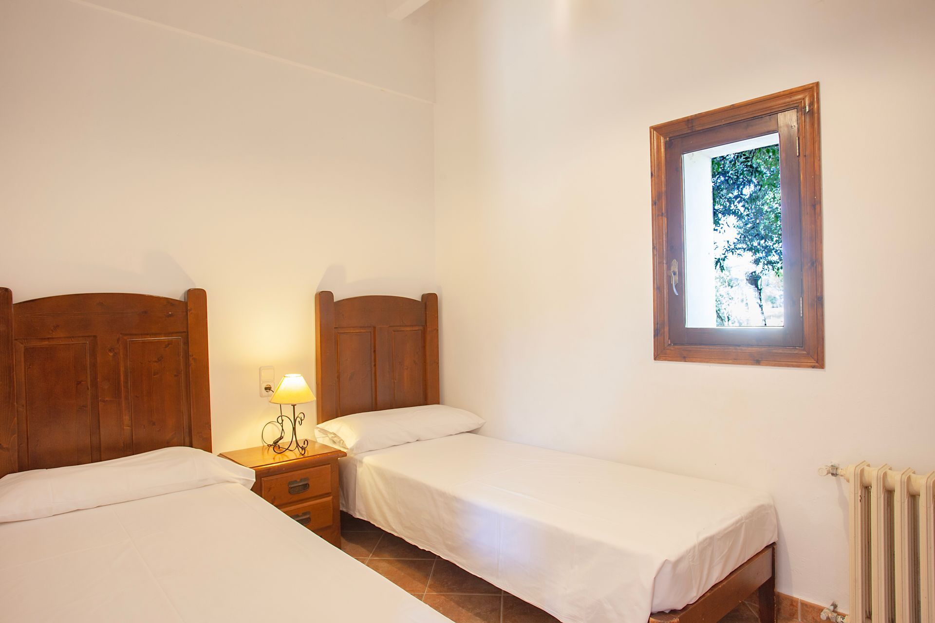 Un dormitorio con dos camas, una mesita de noche y una ventana.