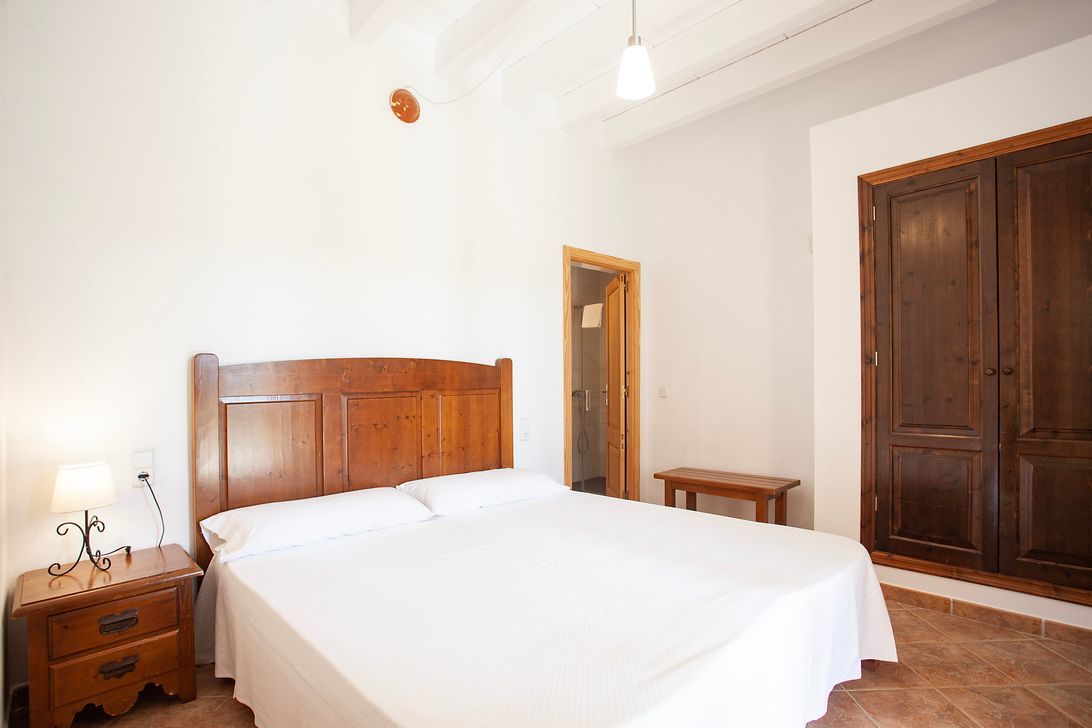 Un dormitorio con una cama grande, mesita de noche y armario.