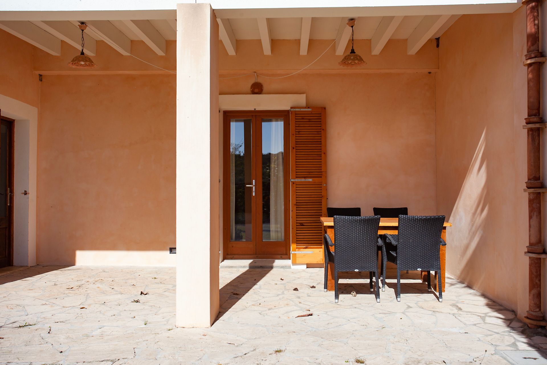 Un patio con mesa y sillas bajo techo.
