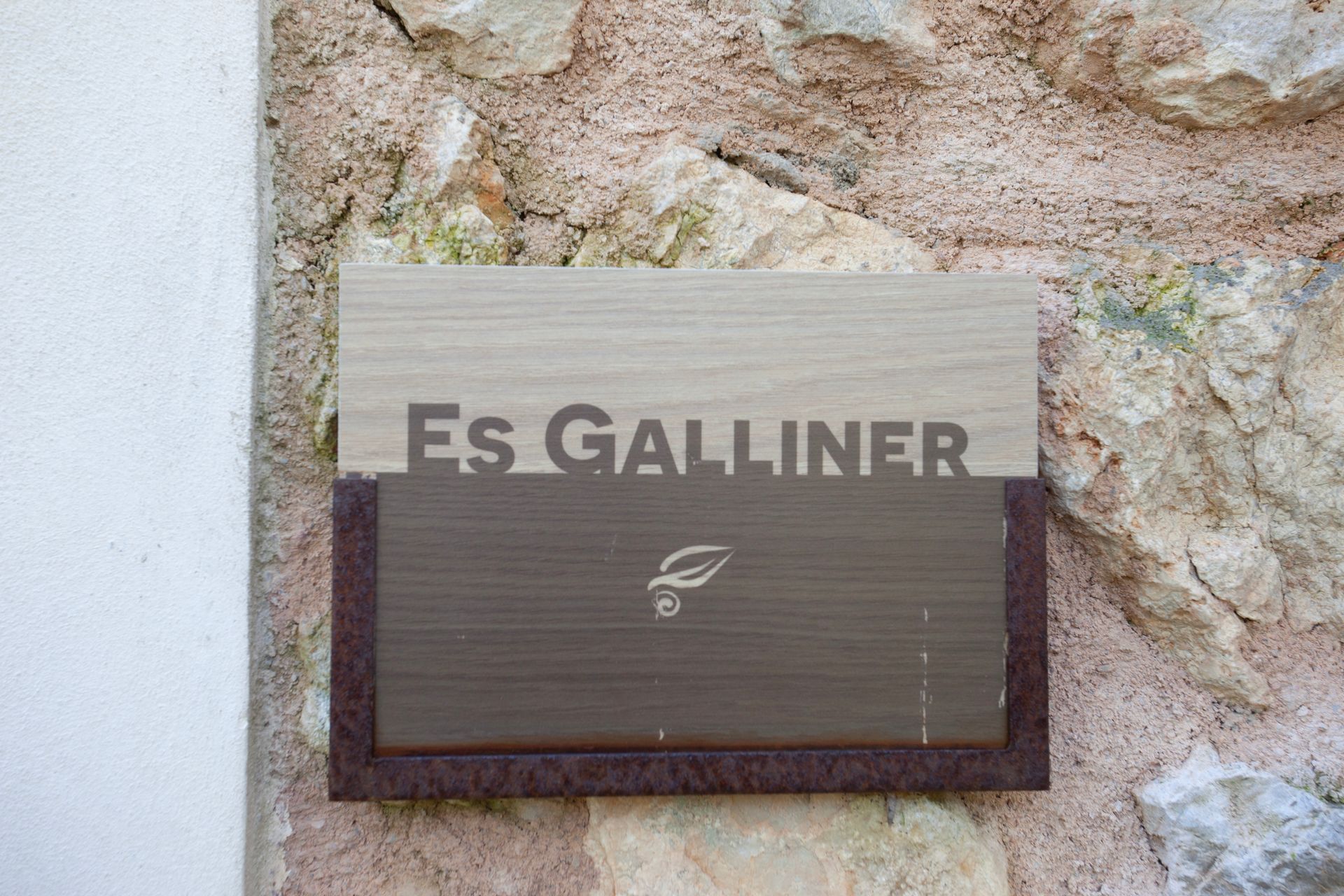 Auf einem Schild an einer Steinmauer steht „Es Galliner“.