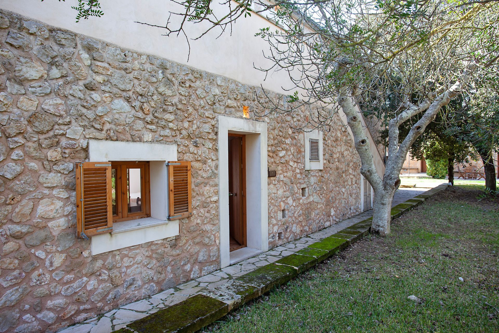 Un edificio de piedra con un árbol delante.