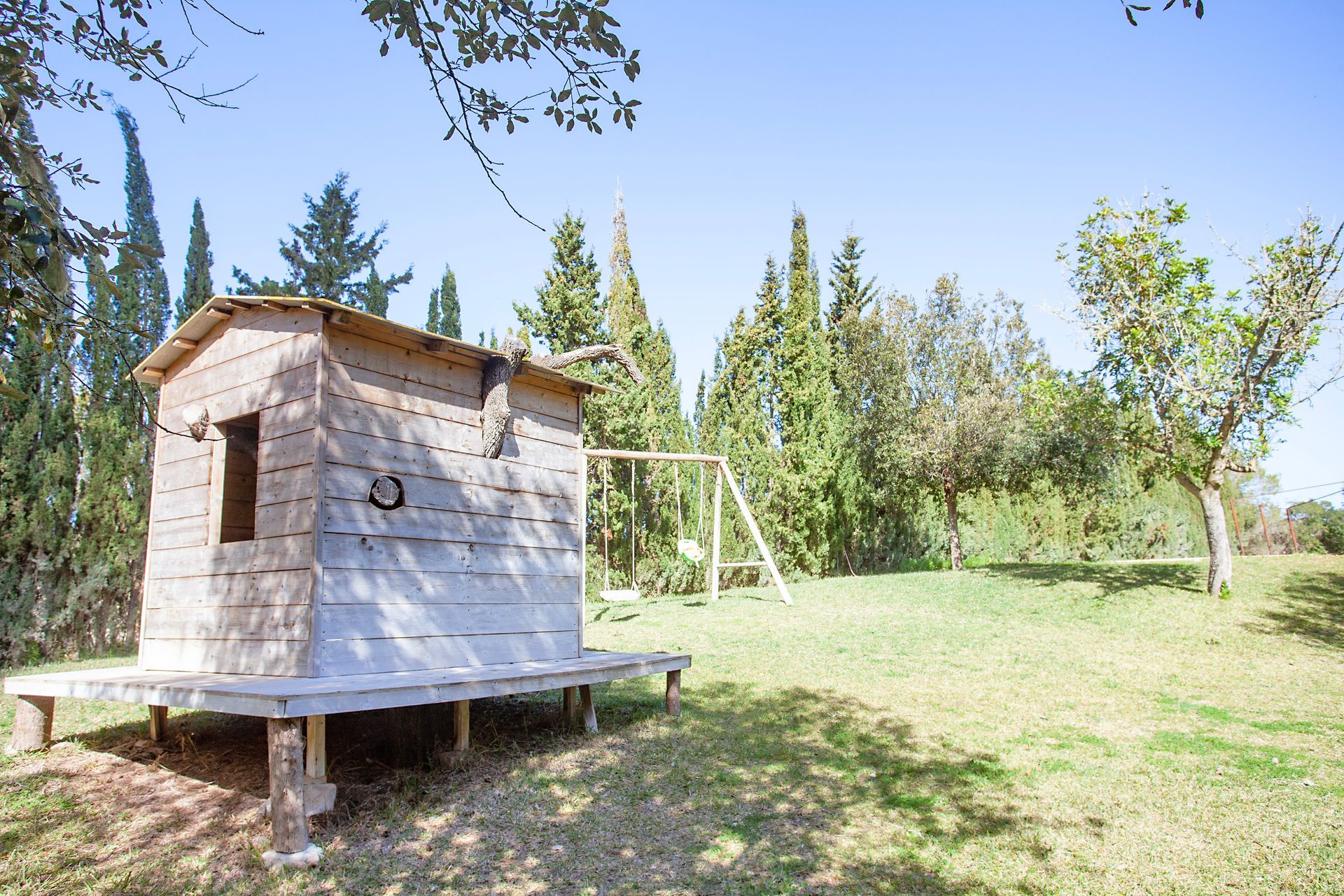 Una pequeña casa de madera se encuentra en medio de un campo de hierba.