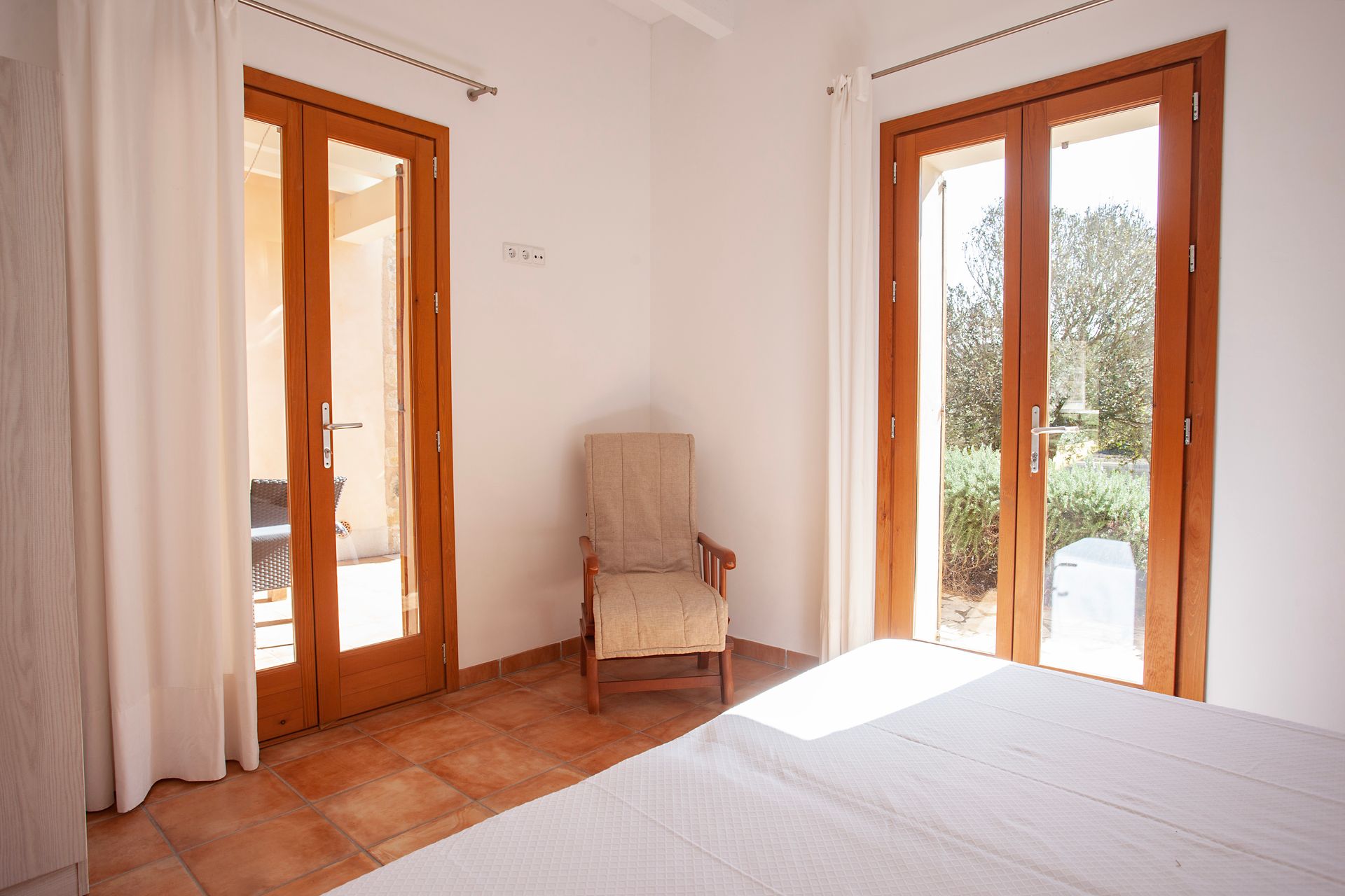 Ein Schlafzimmer mit Bett, Stuhl und Glasschiebetüren