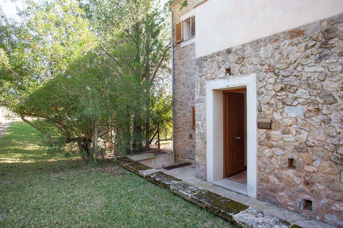 Un edificio de piedra con una puerta y árboles delante de él.