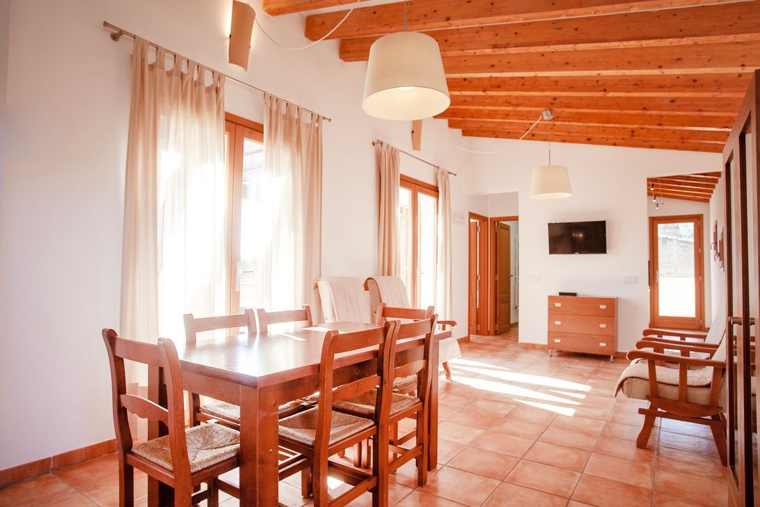 Ein Wohnzimmer mit Esstisch und Stühlen und einem Fernseher.