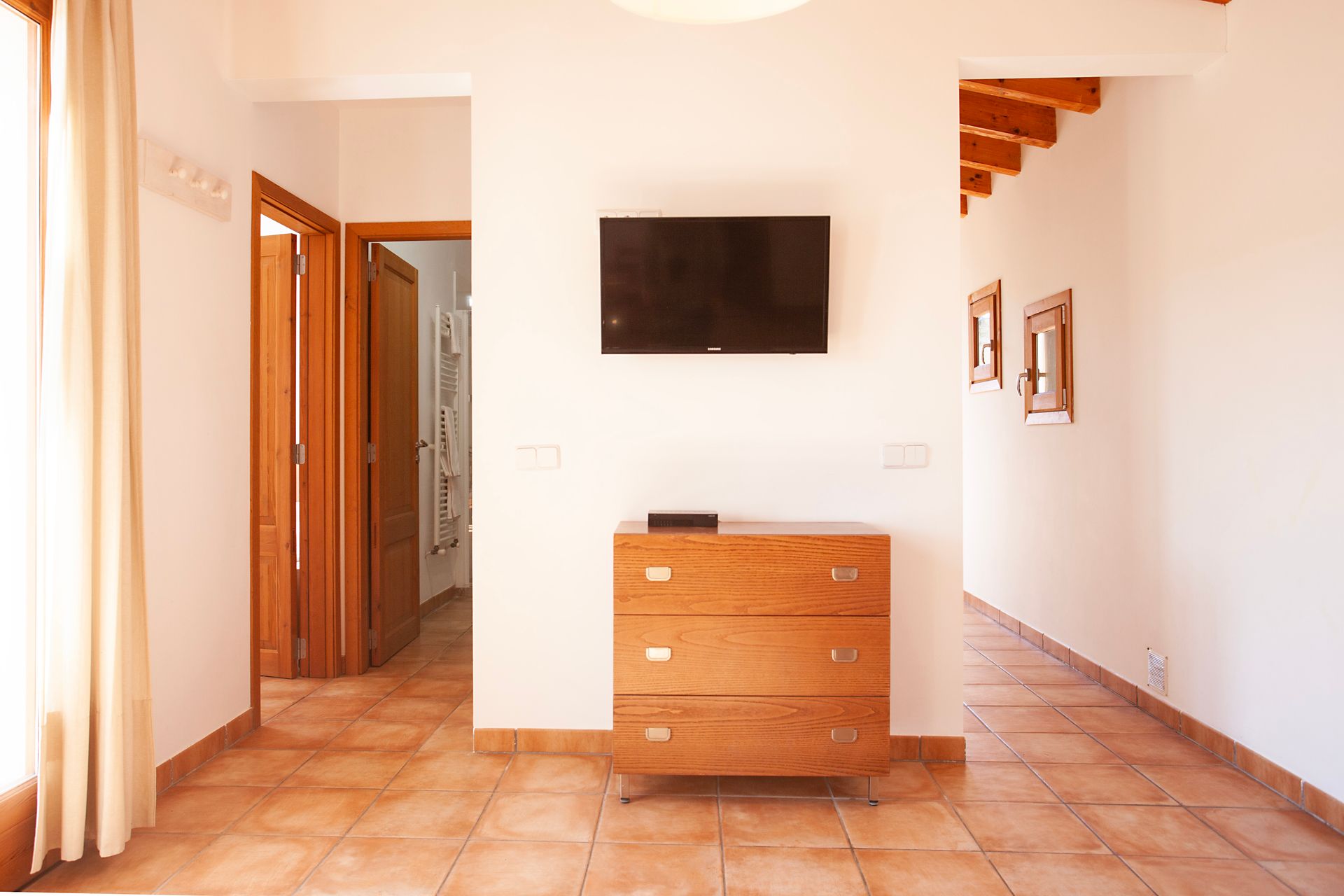 Ein Wohnzimmer mit einer Kommode und einem Flachbildfernseher an der Wand.