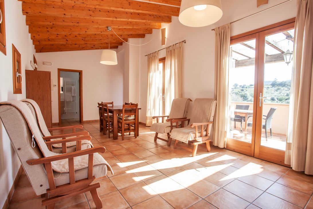 Una sala de estar con un sofá, sillas, una mesa y un balcón.