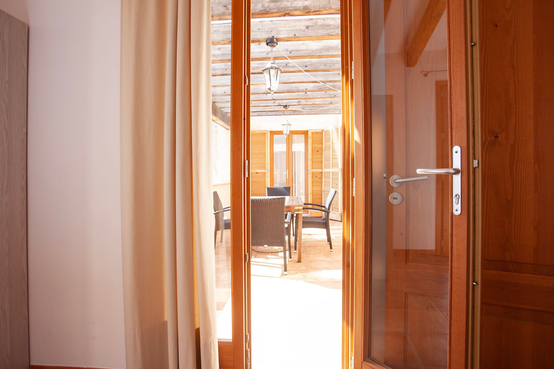 Una puerta de madera se abre a una sala de estar con una mesa y sillas.