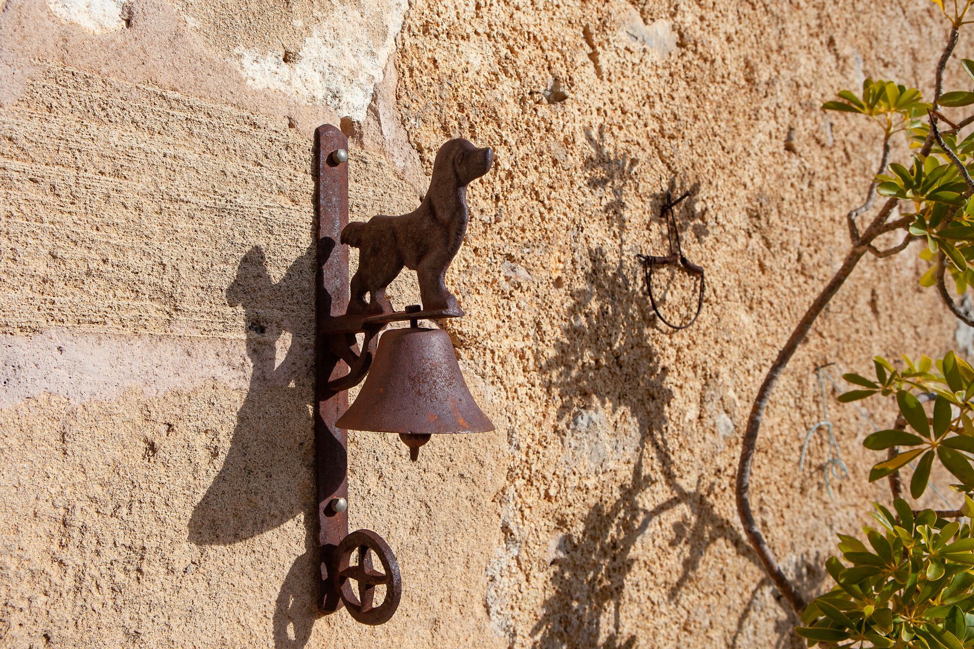 An einer Wand hängt eine rostige Glocke mit einem Hund darauf.