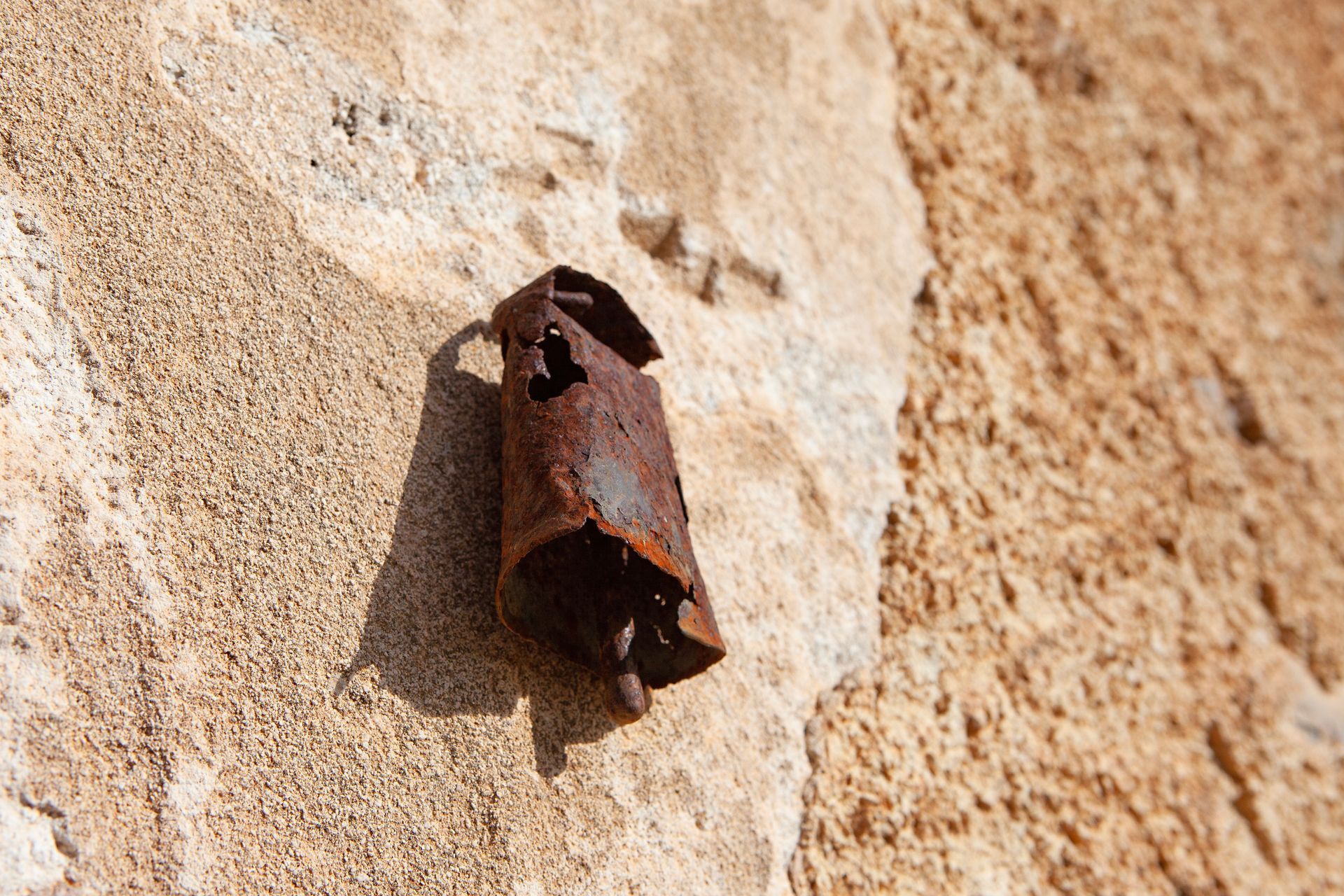 Auf einer Steinmauer liegt ein rostiger Gegenstand.