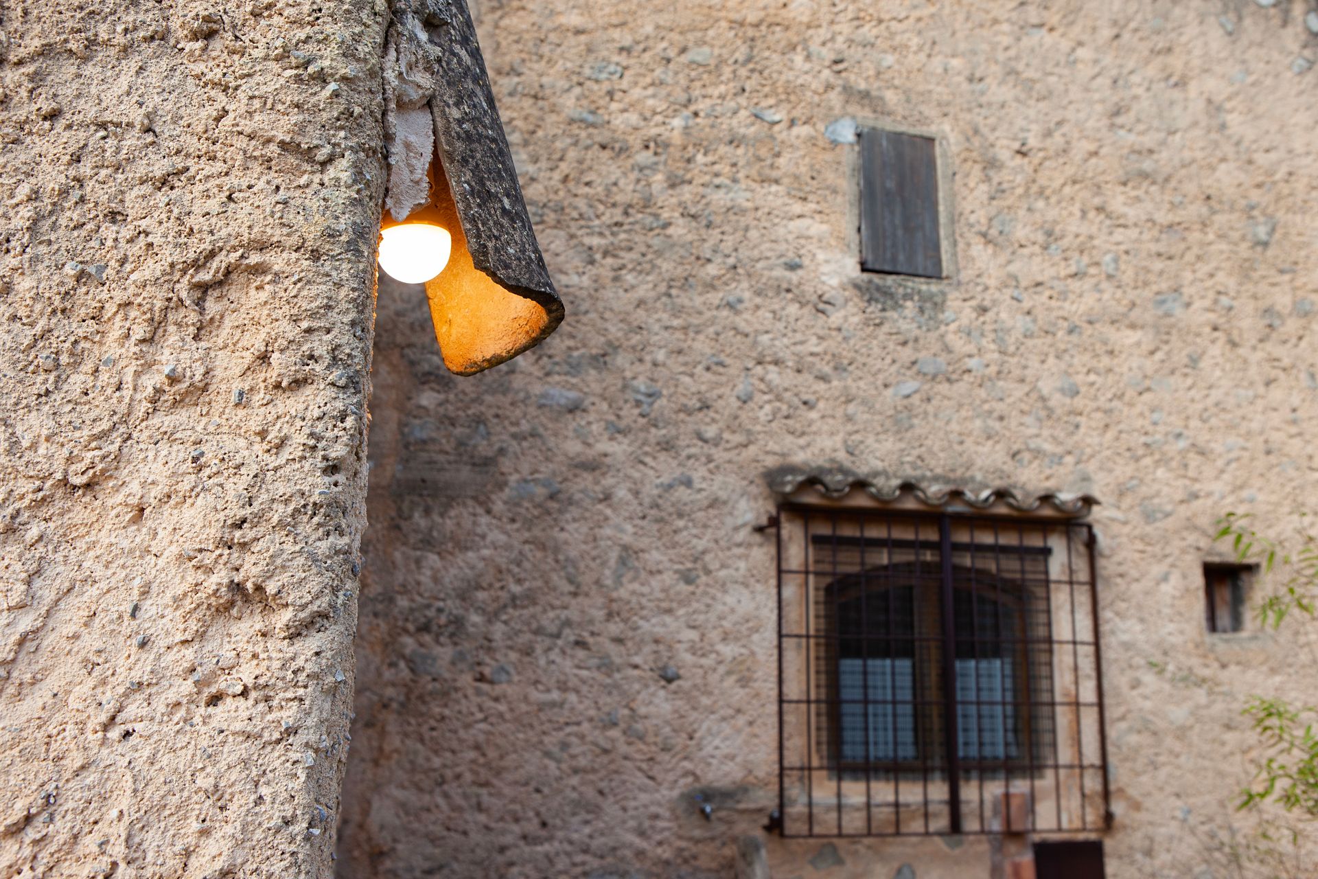 Una pared de ladrillos con una ventana y una lámpara encima.
