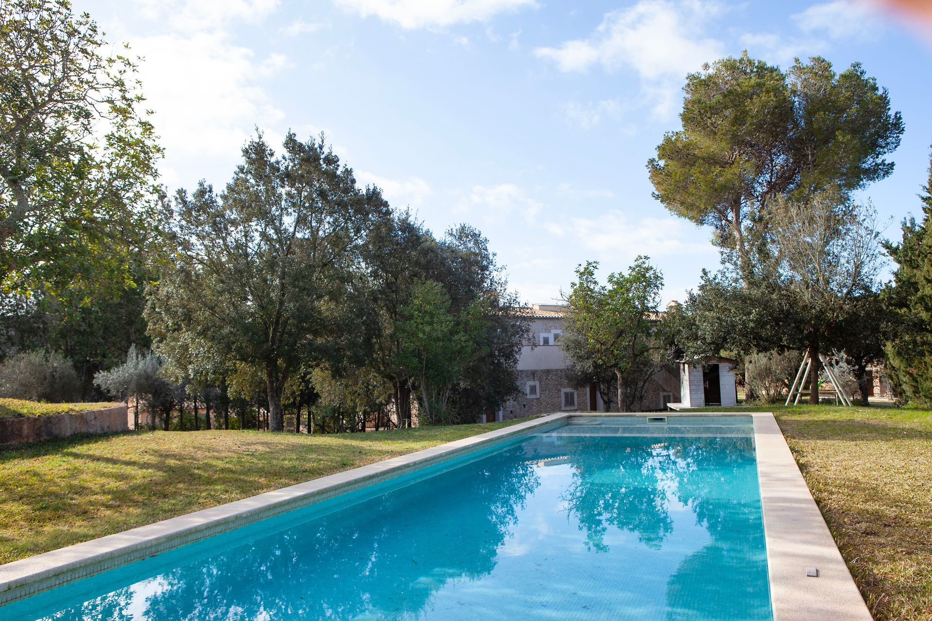 Una gran piscina está rodeada de árboles y césped.
