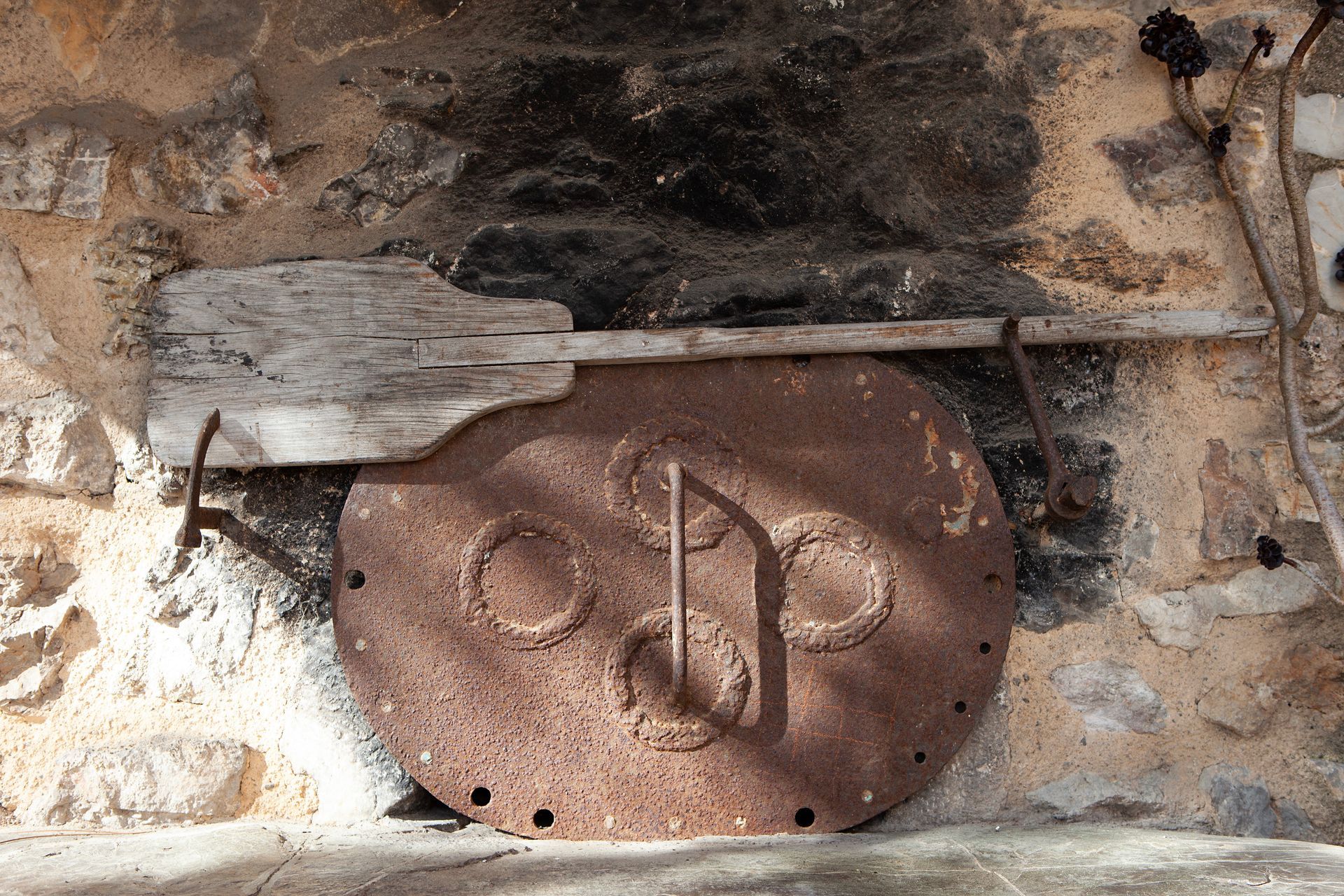 Ein Holzpaddel hängt an einem Metallgegenstand an einer Steinmauer