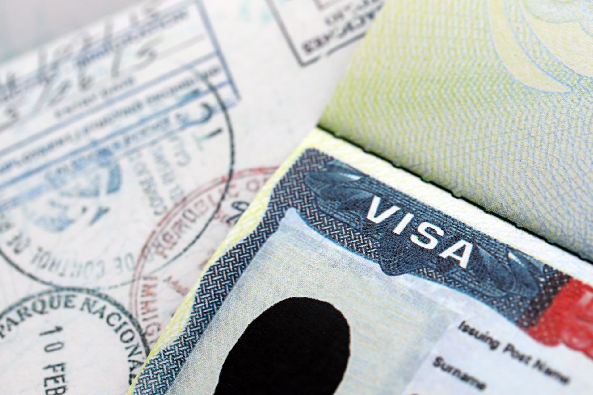 Close-up of a passport open to a visa page, with blue and red details, and stamped markings.