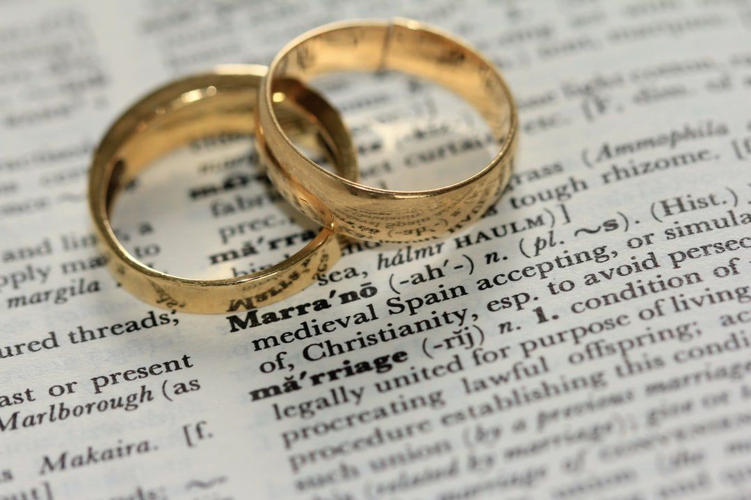 Two gold wedding rings on top of a dictionary page